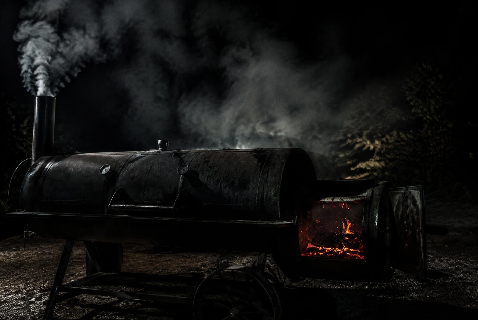 Offset smoker billowing smoke at night